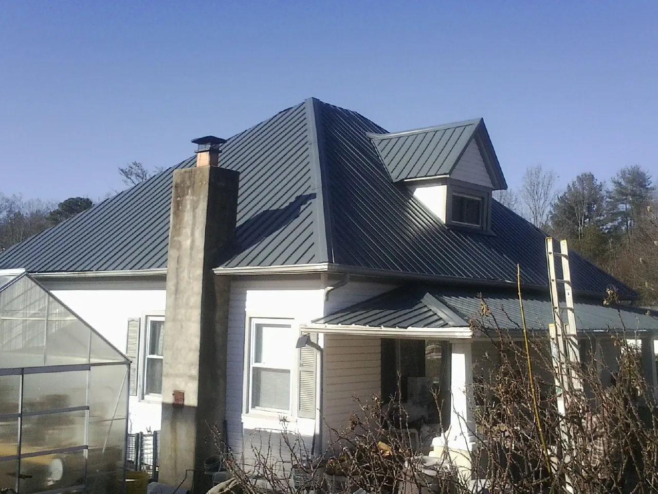 Dark blue standing seam metal roof on a white farmhouse with dormer — Slate & Tile Roof Repair by Roofing Brothers in Plymouth